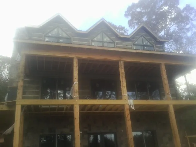 Dormers and porch framing on a large log home under construction — Roof Coating work by our crew in Jacks Creek