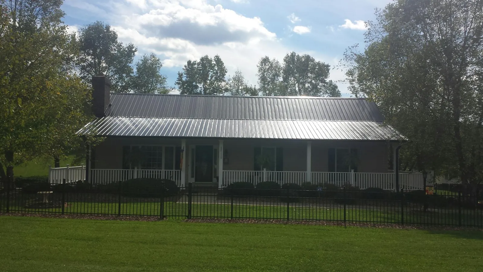 Gray metal roof on a brick ranch with a full width front porch — Gutter Guard Installation work by our crew in Jacks Creek