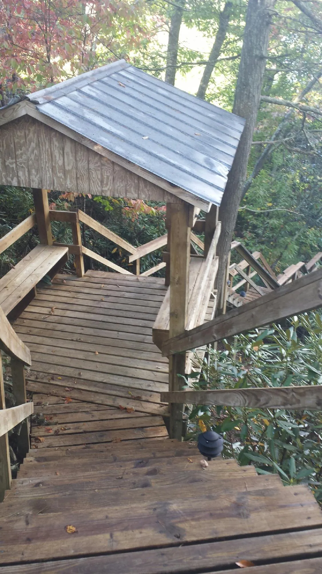 Metal roofed shelter over wooden steps on a wooded walkway — Skylight Repair & Installation work by our crew in Jacks Creek