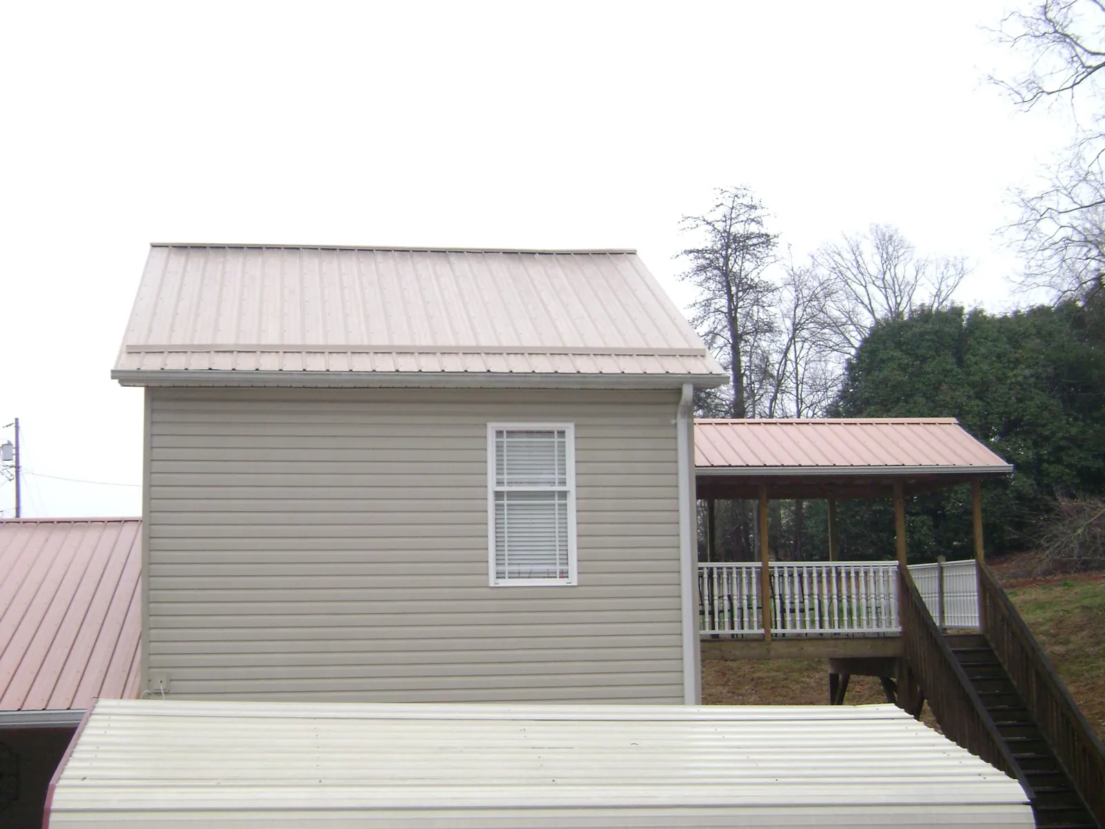 Tan metal roofs on a two story addition and attached porch, from a Roof Replacement job in Jacks Creek