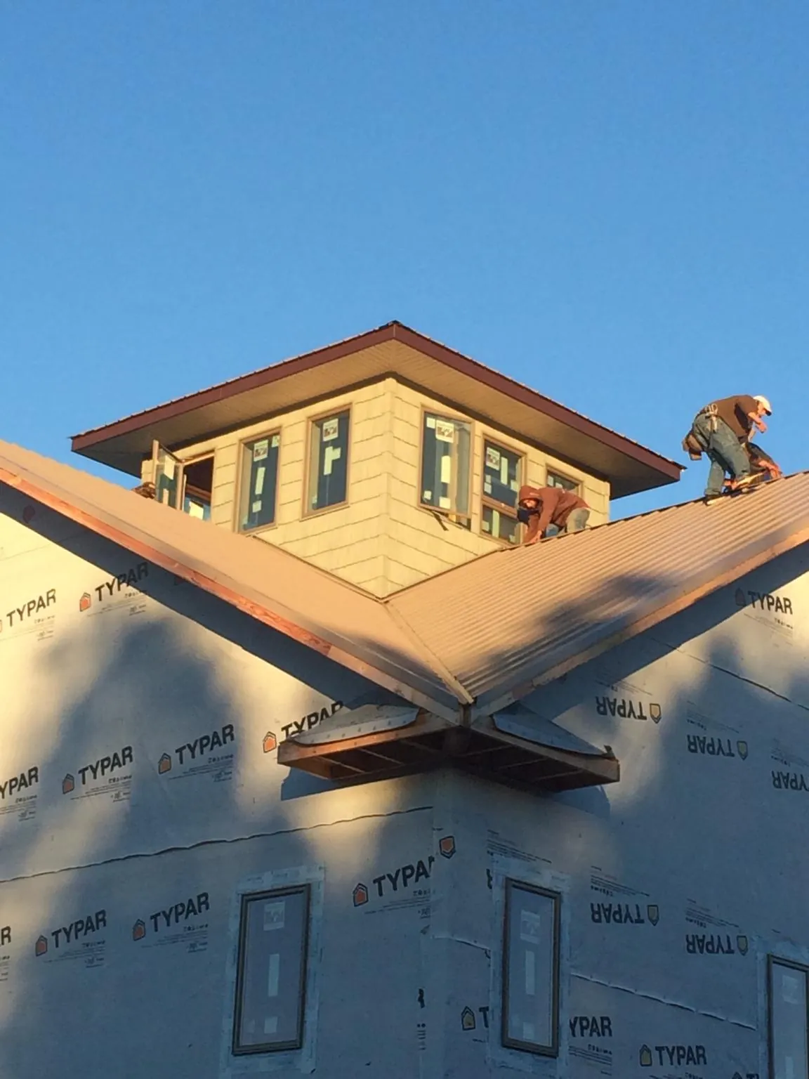 Roofers working around a rooftop cupola on a new metal roof at sunset — Roof Waterproofing in Jacks Creek by Roofing Brothers